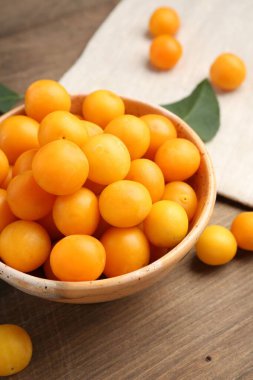 Olgun sarı kiraz erikleri ve yapraklar ahşap masada, yakın plan.