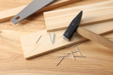 Metal çiviler, çekiç, kalaslar ve tahta masa üzerinde testere.