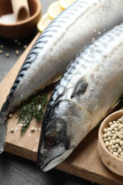 Siyah masada taze çiğ uskumrular ve baharatlar, yakın plan. Deniz ürünleri lezzetleri.