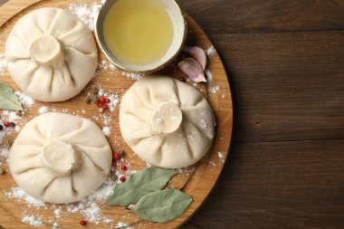 Biber, un ve defne yapraklarıyla ahşap masa üzerinde pişmemiş khinkaliler (hamur köfteleri). Metin için boşluk