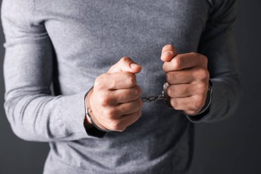 Gri arka planda metal kelepçeli adam, yakın plan.