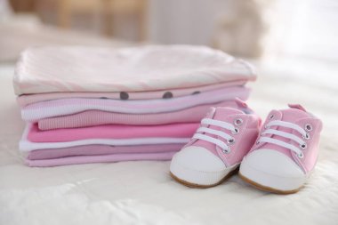 Temiz bebek kıyafetleri ve çarşafların üzerindeki ayakkabılar.