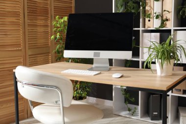 Ofisinde modern bilgisayar ve çiçek dekoru olan şık bir iş yeri. Biyofilik iç tasarım