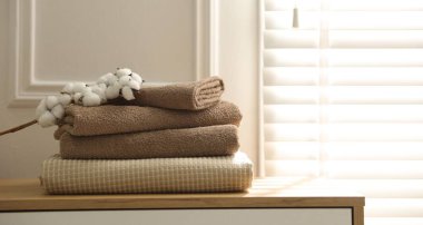 Beyaz duvarın yakınındaki tahta çekmecelerde temiz havlular ve pamuk çiçekleri yığını. Metin için boşluk