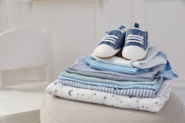 Temiz bebek kıyafetleri ve pouf kapalı yerde ayakkabı yığını, mesaj için yer