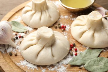 Biber, un ve defne yapraklarıyla pişirilmemiş khinkaliler (hamur köfteleri) ahşap masada, yakın plan