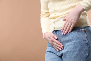 Koyu bej arka planda sistit belirtileri gösteren bir kadın, yakın plan. Metin için boşluk