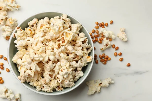 Lezzetli patlamış mısır ve mısır taneleri beyaz mermer masada, düz yerde.