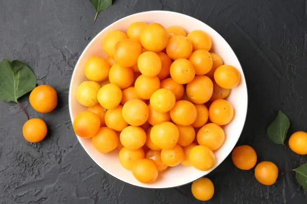 Olgun sarı kiraz erikleri ve yaprakları siyah masanın üzerinde, düz yatıyordu.