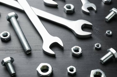 Birçok metal anahtar, cıvata ve somun siyah ahşap masa, yakın plan