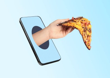 Yemek siparişi ve teslimat servisi. Lezzetli pizza dilimli bir kadın eli, cep telefonu ekranının dışında açık mavi arka planda, yakın plan