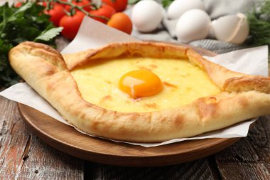 Lezzetli khachapuri peyniri, yumurtası ve diğer ürünleri ahşap masada, yakın plan.