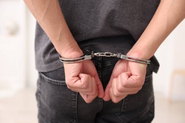 Bulanık ışıklı arka planda metal kelepçeli adam, yakın plan.