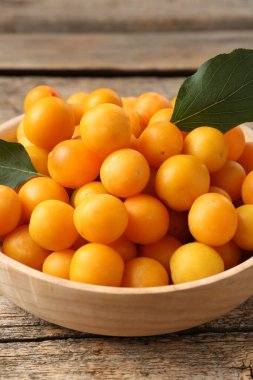 Olgun sarı kiraz erikleri ve yapraklar ahşap masada, yakın plan.