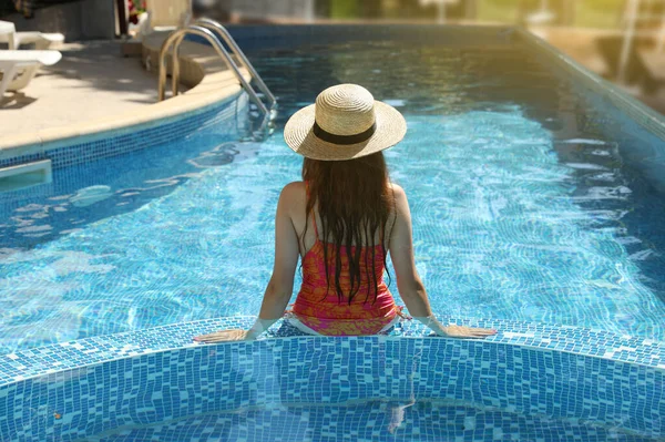 Deniz kıyısındaki havuzda hasır şapkalı kız.