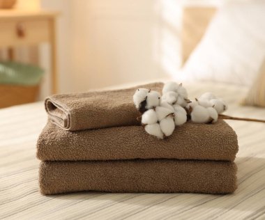 Evdeki çarşafların üzerinde temiz havlular ve pamuk çiçekleri yığını.