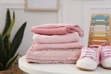 Temiz bebek kıyafetleri ve aksesuarlar beyaz masa içinde, yakın plan.