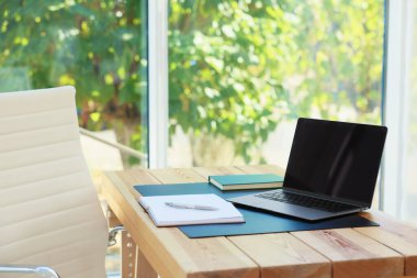 Ev işyerinde. Laptop ve kırtasiye malzemeleri ahşap masada.