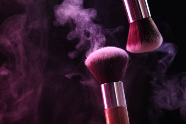 Renkli göz gölgeli makyaj fırçaları siyah arka planda neon ışıkları, yakın plan. Metin için boşluk