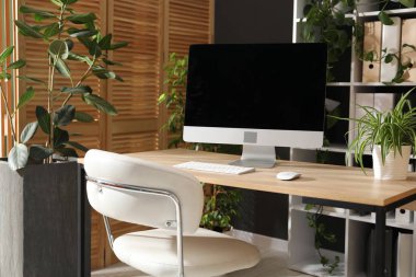 Ofisinde modern bilgisayar ve çiçek dekoru olan şık bir iş yeri. Biyofilik iç tasarım