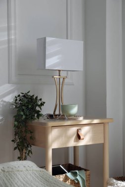 Yatağın içinde lamba ve diğer dekorlarla birlikte komodinin yanında.