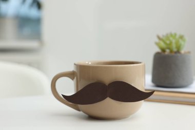 Babalar Günün kutlu olsun. Kağıt bıyıklı kupa ve kitaplarla kapalı masa, yakın plan.