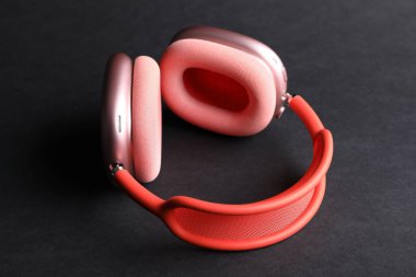 Siyah arka planda bir çift şık pembe kulaklık, yakın plan.