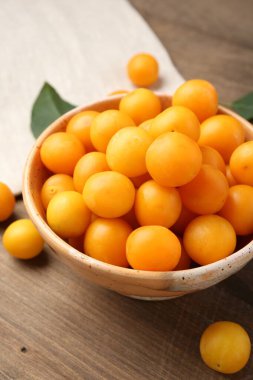 Olgun sarı kiraz erikleri ve yapraklar ahşap masada, yakın plan.