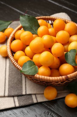 Olgun sarı kiraz erikleri ve koyu ahşap masada yapraklar, yakın plan.