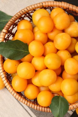 Olgun sarı kiraz erikleri ve yaprakları masanın üstünde, üst tarafta.