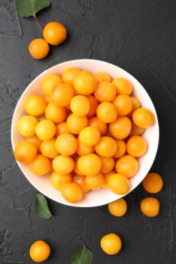 Olgun sarı kiraz erikleri ve yaprakları siyah masanın üzerinde, düz yatıyordu.