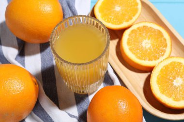 Taze sıkılmış portakal suyu, meyveler ve havlu mavi ahşap masada, yakın plan.