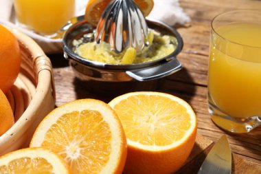 Taze sıkılmış portakal suyu, meyve suyu ve meyve sıkacağı ahşap masada, yakın plan.