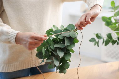 Çiçekçinin ahşap masasında okaliptüs dallarından güzel bir buket yapıyor.