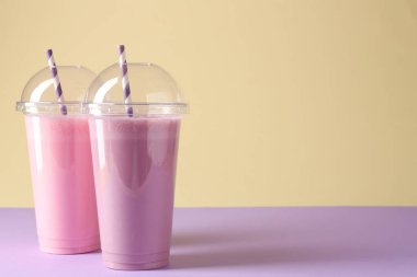 Renkli arka planda plastik bardaklarda lezzetli milkshake 'ler, metin için boşluk