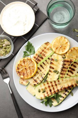 Gri desenli masada servis edilen balkabağı tohumlu, limonlu ve maydanozlu lezzetli kabak dilimleri.