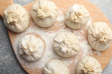 Gri masa üzerinde un bulunan pişmemiş khinkaliler (hamur tatlısı), üst görünüm