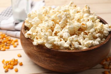 Lezzetli patlamış mısır ve mısır taneleri açık ahşap masada, yakın plan.