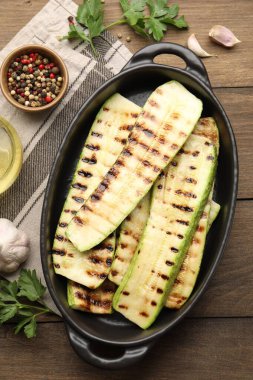 Lezzetli ızgara kabak dilimleri ve ahşap masada baharatlar, düz uzanmış.