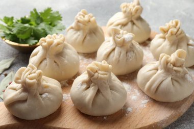 Gri masada un ve maydanozlu pişmemiş khinkaliler (hamur tatlısı), yakın plan.