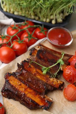 Kızarmış biftek pirzolası, mikroyeşillikler, domatesler ve soslar masada, yakın plan.