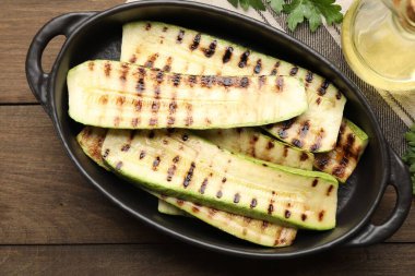 Lezzetli ızgara kabak dilimleri, ahşap masada yağlı ve maydanozlu.