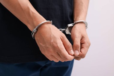 Hafif arka planda metal kelepçeli adam, yakın plan.