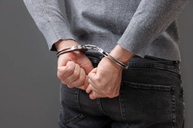 Gri arka planda metal kelepçeli adam, yakın plan.