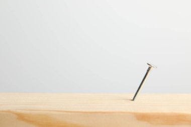 Açık gri arka planda, tahta tahtada metal çivi, yakın plan. Metin için boşluk