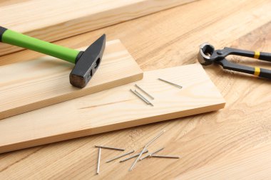 Metal çiviler, çekiç, tahta ve kıskaçlar ahşap masa, yakın plan