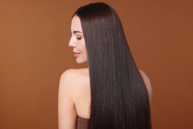 Kahverengi arka planda katman prosedüründen sonra güzel düz saçlı bir kadın.