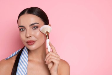 Pembe arka planda makyaj fırçası olan güzel kadın, metin için boşluk