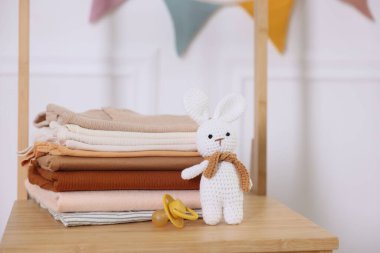 İçerideki ahşap şifoniyerde temiz bebek kıyafetleri ve aksesuarlar yığını.