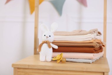 İçerideki ahşap şifoniyerde temiz bebek kıyafetleri ve aksesuarlar yığını.